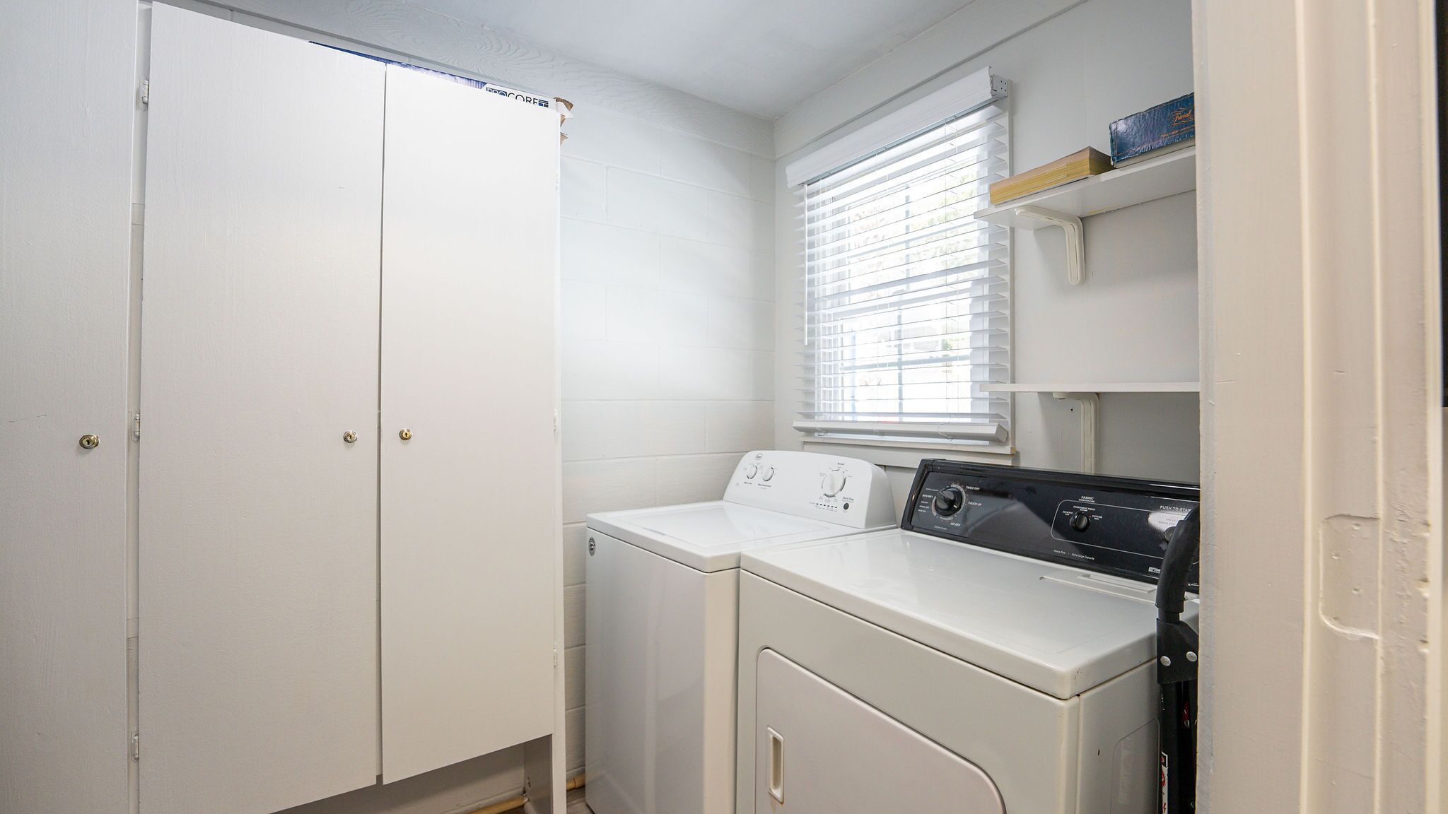 A laundry room with a white washing machine, a dryer, and a door with a lock.