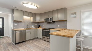 Una cocina moderna con armarios grises, electrodomésticos de acero inoxidable y una isla de madera.