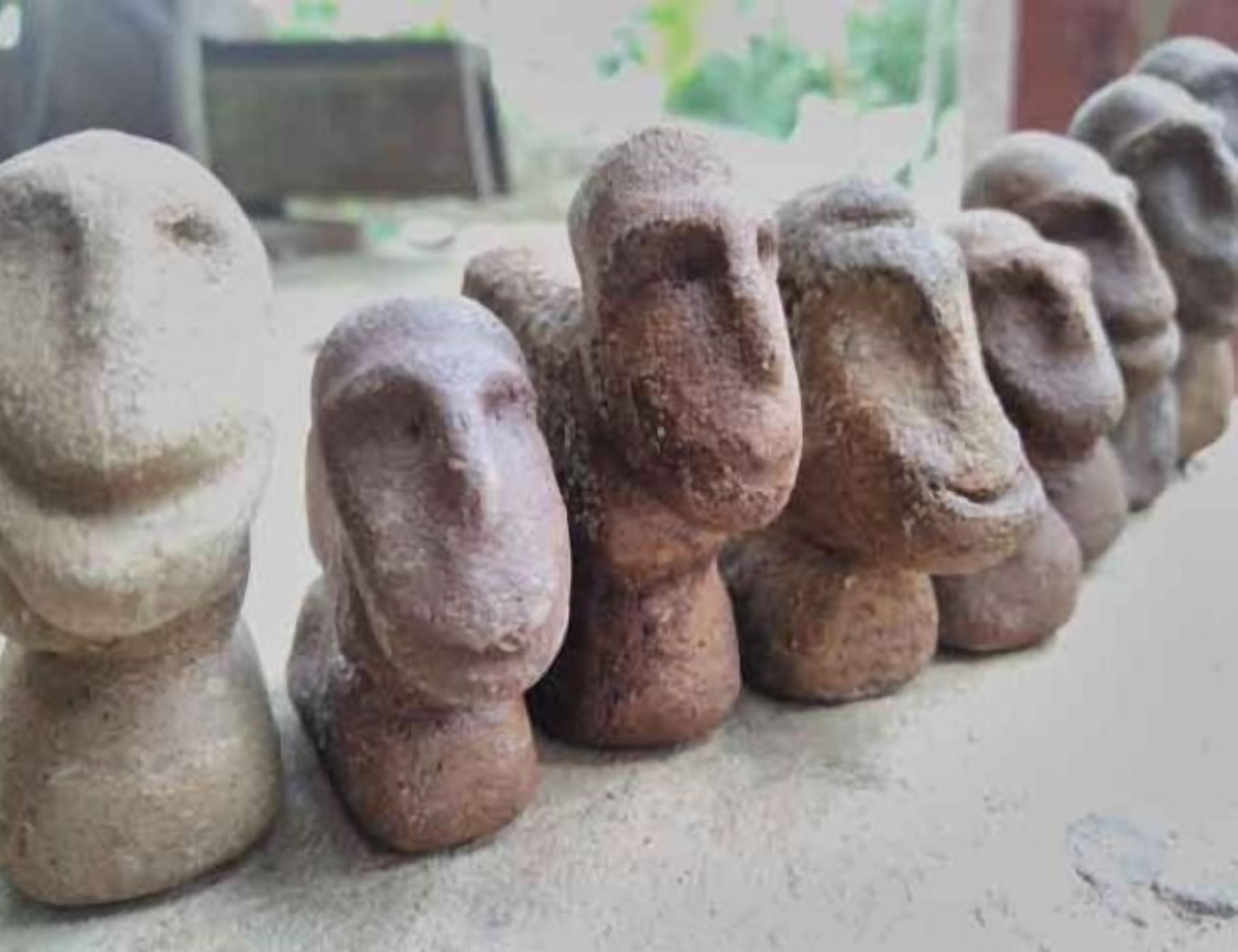 Une rangée de sculptures en pierre aux traits du visage différents.
