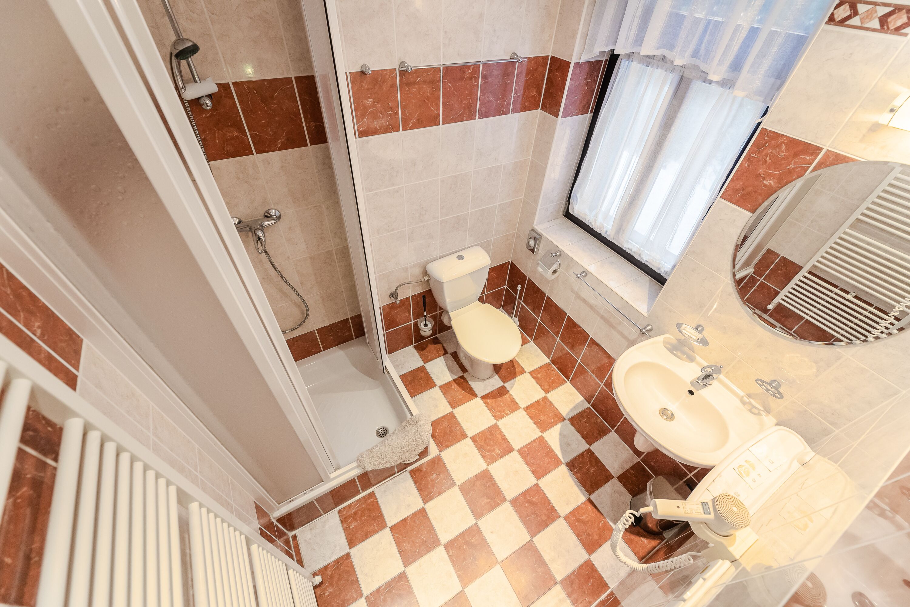A bathroom with a checkered floor, a toilet, a sink, and a shower.