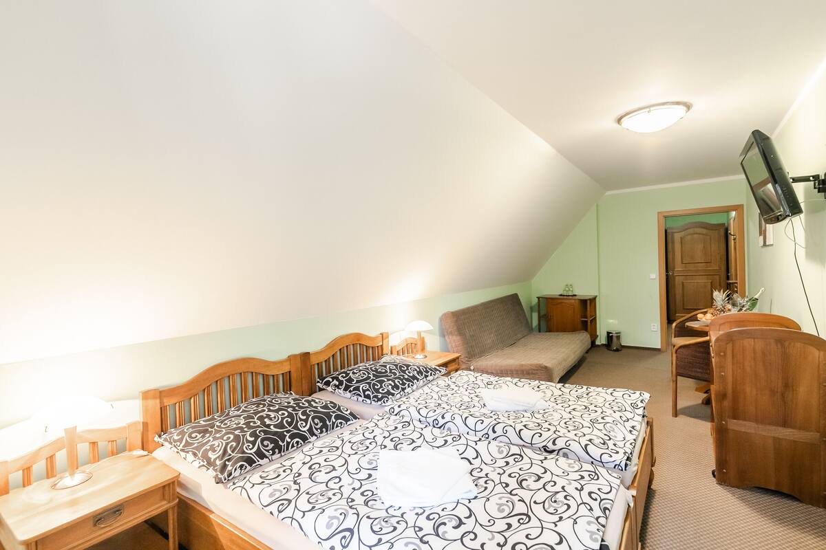 Une chambre avec deux lits, un bureau, une chaise, un téléviseur fixé au mur et une porte donnant sur une autre pièce.