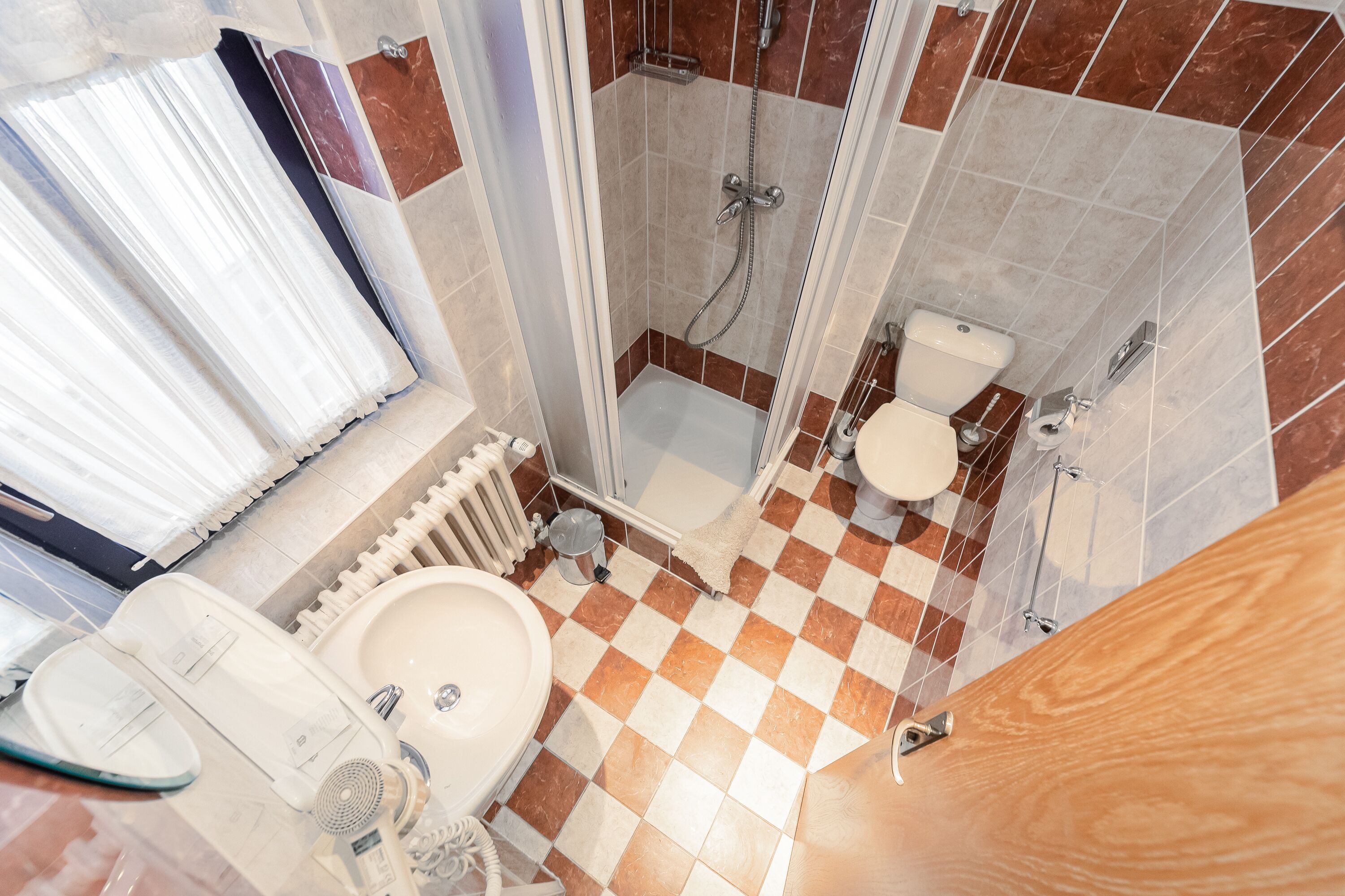 Une salle de bain avec un carrelage à motifs géométriques, une douche, des toilettes et un lavabo.
