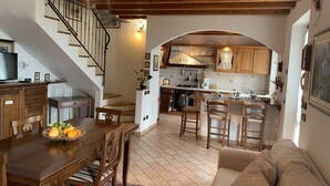 A cozy kitchen with wooden cabinets, a dining area with a wooden table and chairs, and a staircase leading to an upper level. - Villa Stefano lake view (Gargnano)