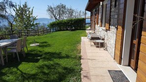 A patio with a table and chairs, a stone pathway, and a view of the sea. - Villa Stefano lake view (Gargnano)