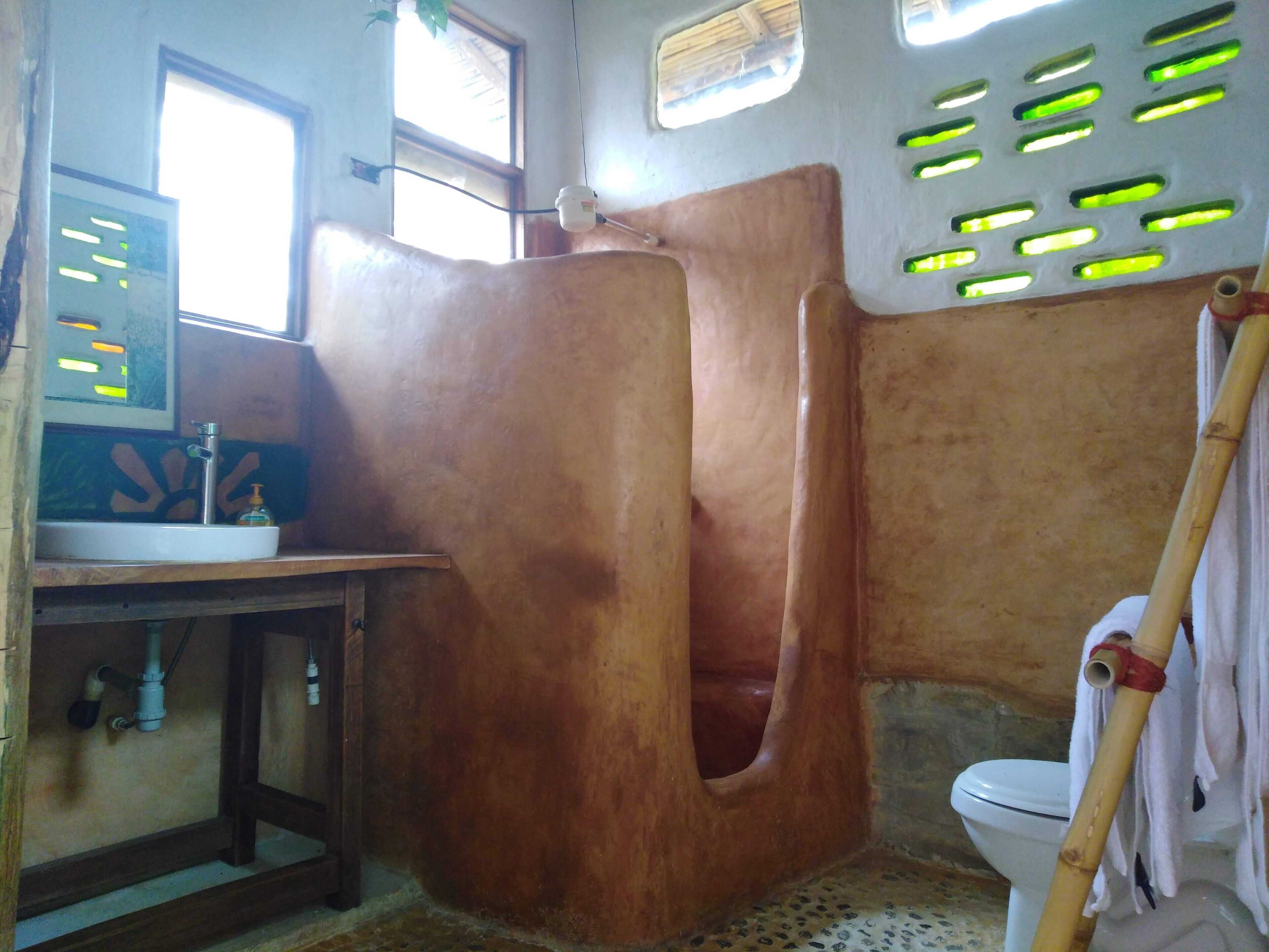 A bathroom with a wooden bathtub, a sink with a mirror, and a toilet.