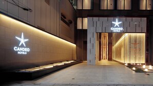 Una entrada de hotel moderna con señalización iluminada, fachada limpia y un camino bien iluminado que conduce a la entrada.