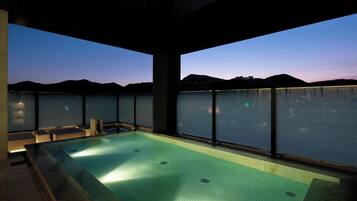 A rooftop infinity pool with a city view at dusk.