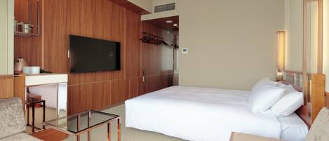 A hotel room with a large bed, a desk with a chair, a television, and a mirror.