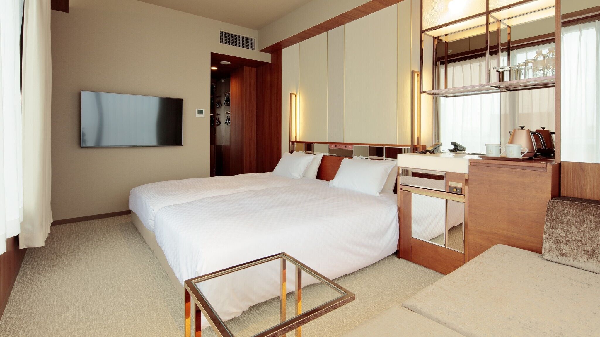 A hotel room with a bed, a TV, a desk with a mirror, and a coffee maker.