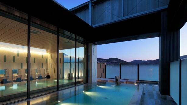 Un edificio moderno con piscina cubierta de vidrio y vista al agua.