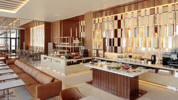 Un moderno vestíbulo de hotel con una zona de bar central, asientos y un mostrador para buffet.