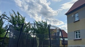 Un trampolín en un patio trasero con una casa al fondo.
