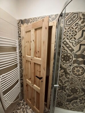 A bathroom with a wooden door, a shower area, and patterned tiles. - Villa Oliva/entire house/free WiFi and Parking (Ceský Krumlov)