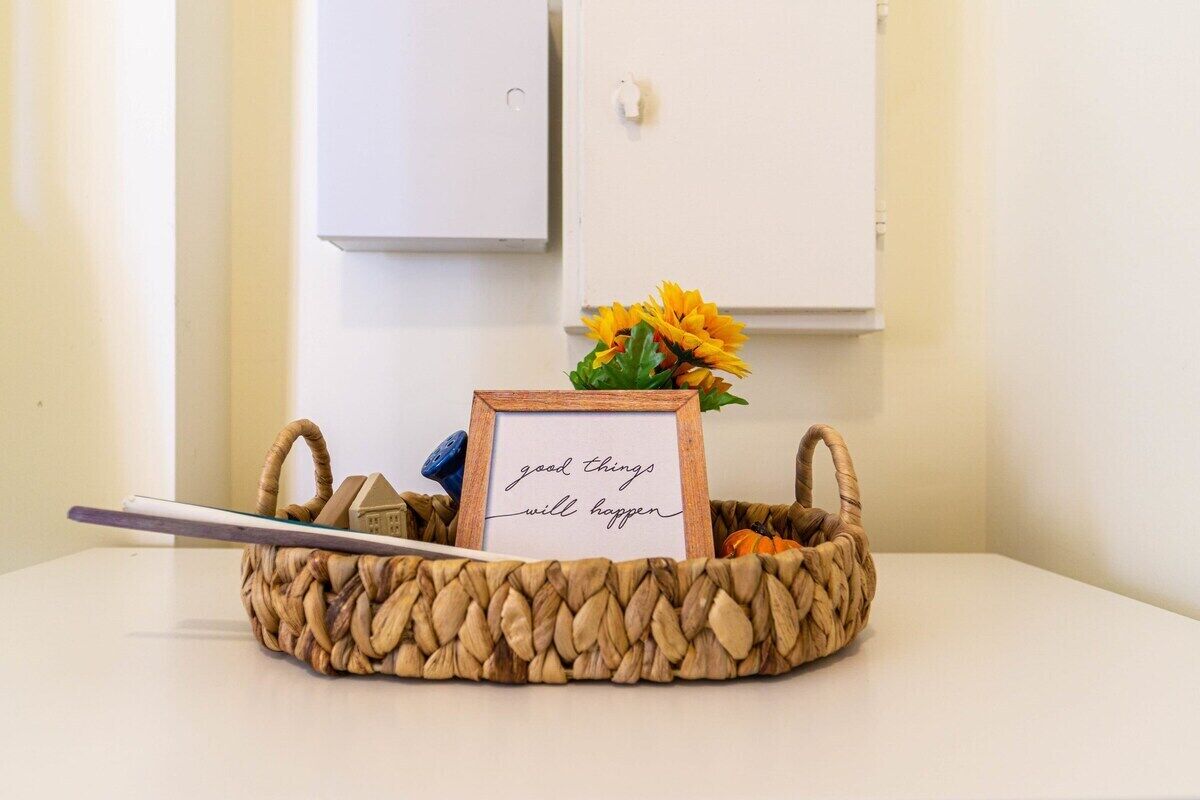 A woven basket with a framed sign saying "good things will happen" and a small house model.