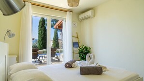 Habitación de hotel con cama, escritorio, lámpara, reloj y vistas al exterior.