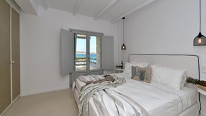 Quarto com cama, mesa de cabeceira, janela com vista e luminária pendente.