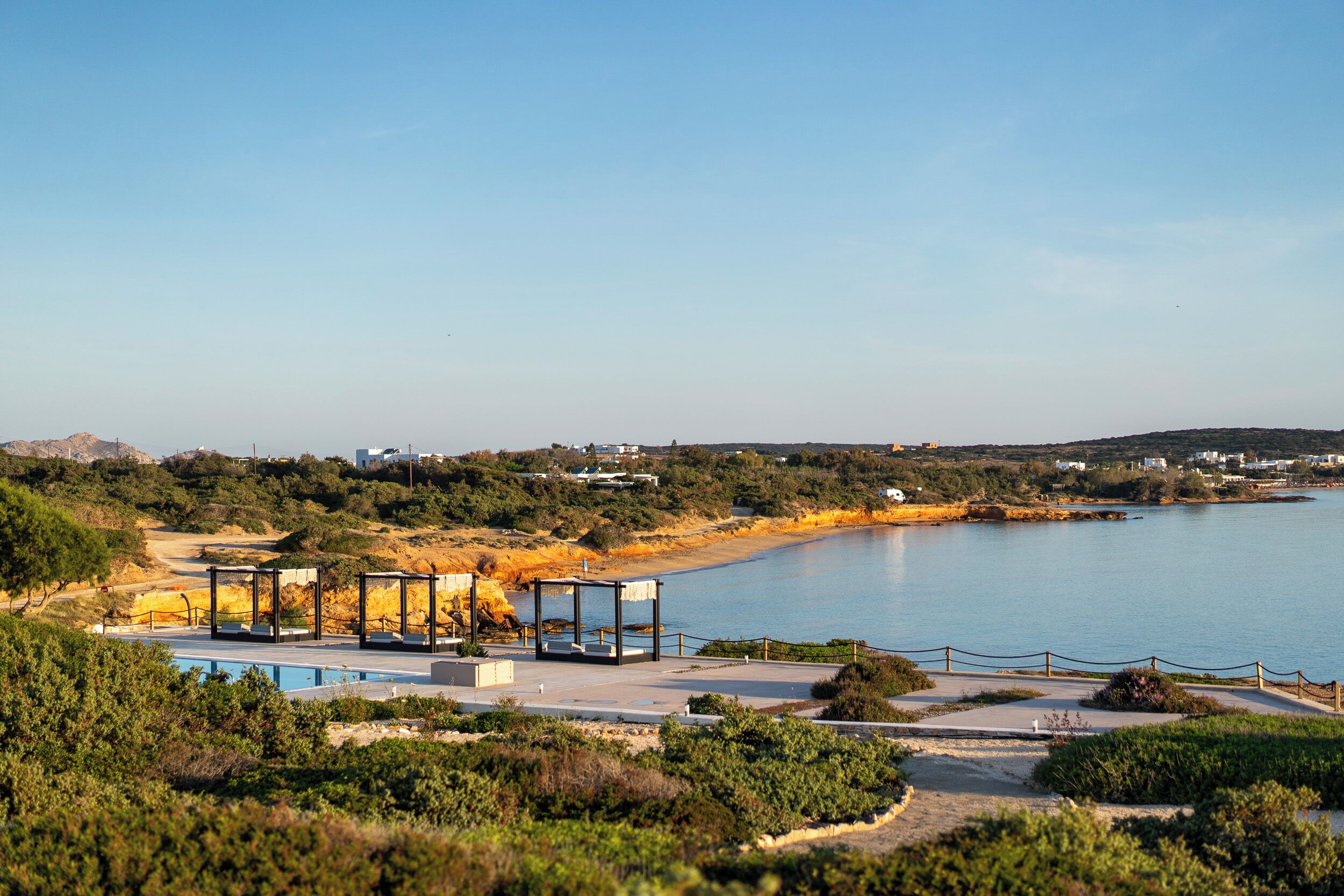 A coastal resort with a swimming pool, lounge chairs, and a view of the sea.