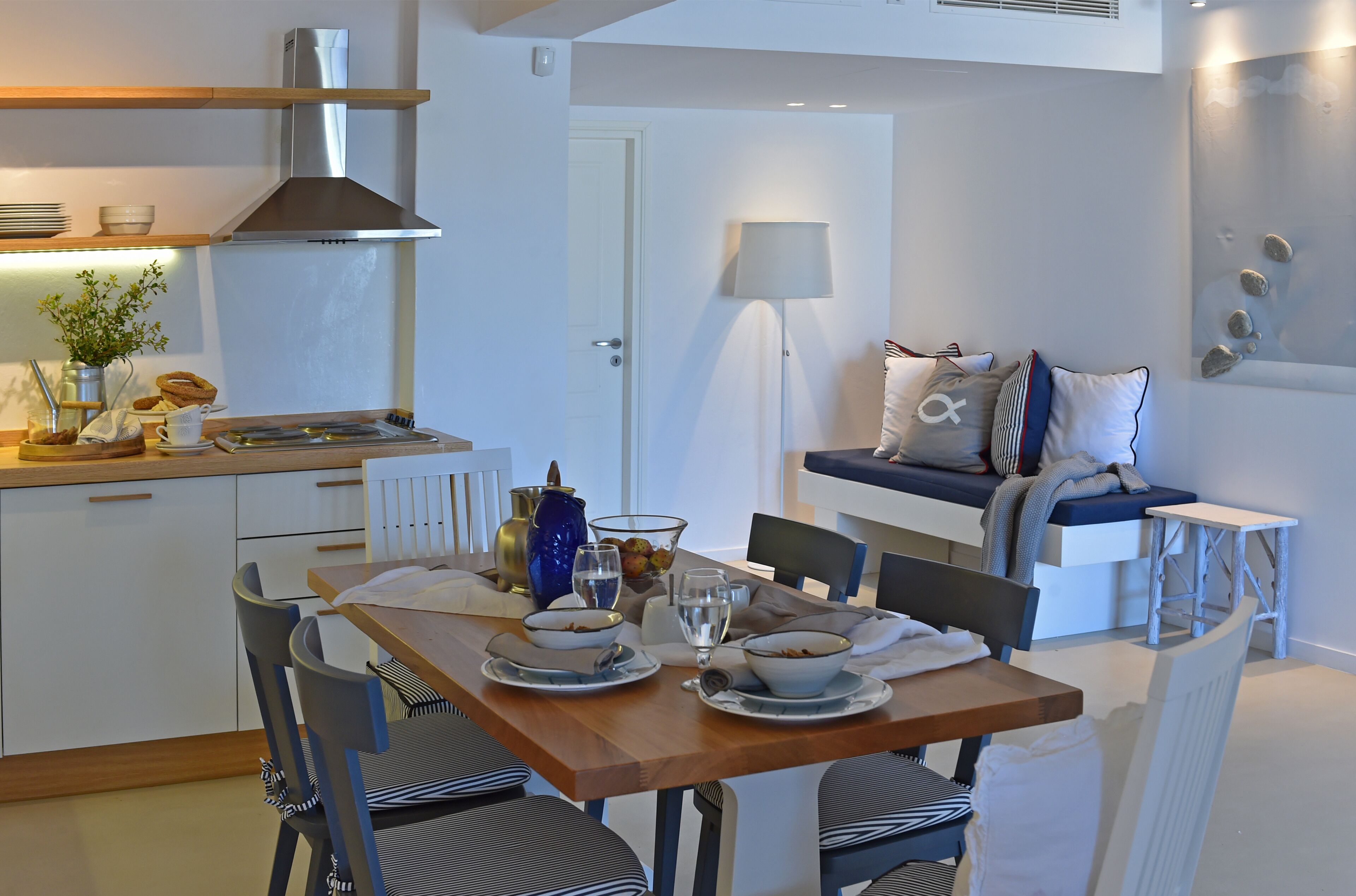 A modern kitchen with white cabinets, a stainless steel range hood, and a dining area with a wooden table and chairs.