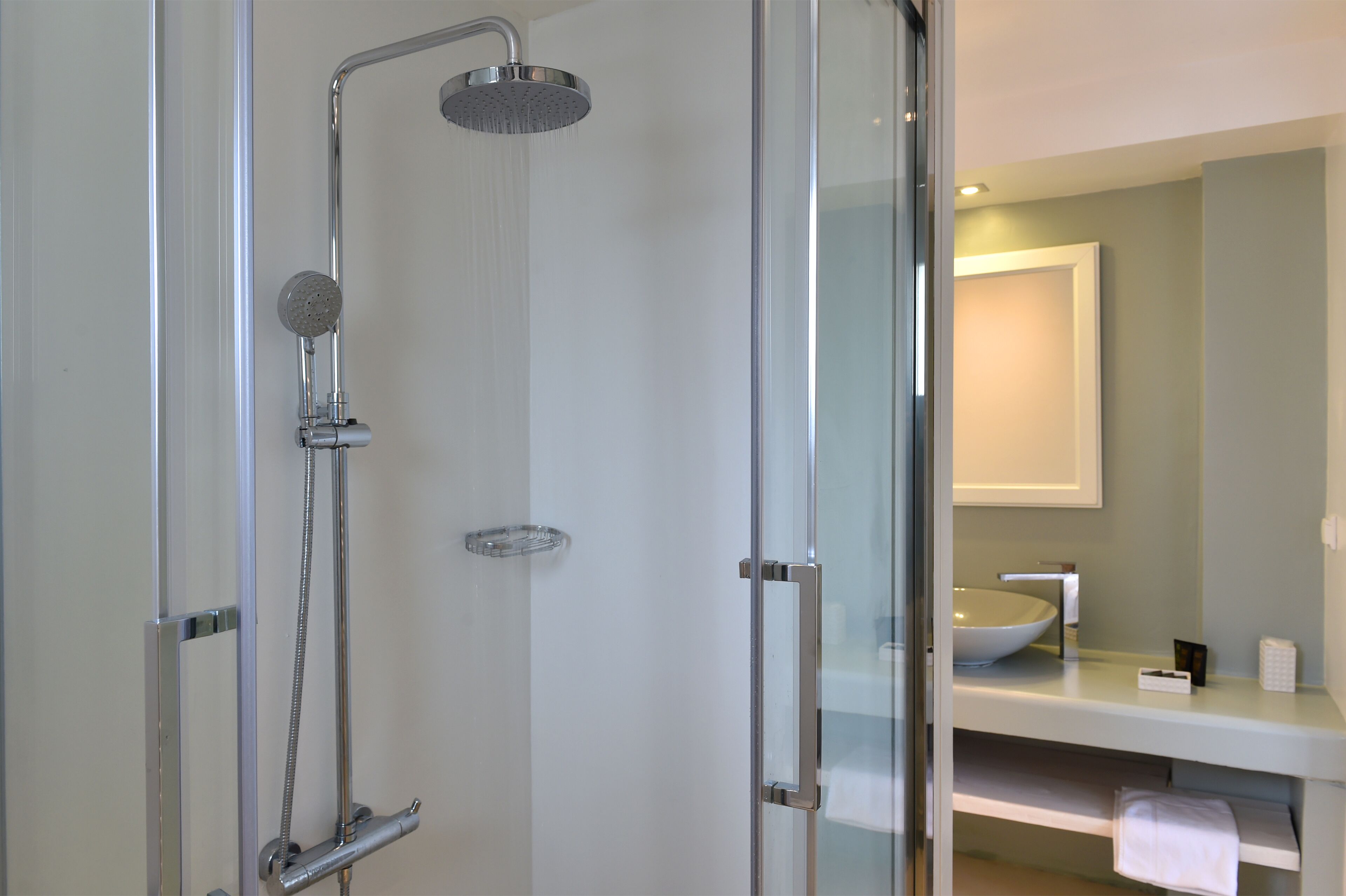 A modern bathroom with a glass-enclosed shower, a white sink, and a mirror above the sink.