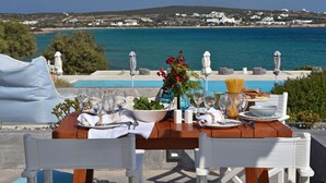 Uma mesa posta para refeição, com vista para o mar e paisagem costeira.