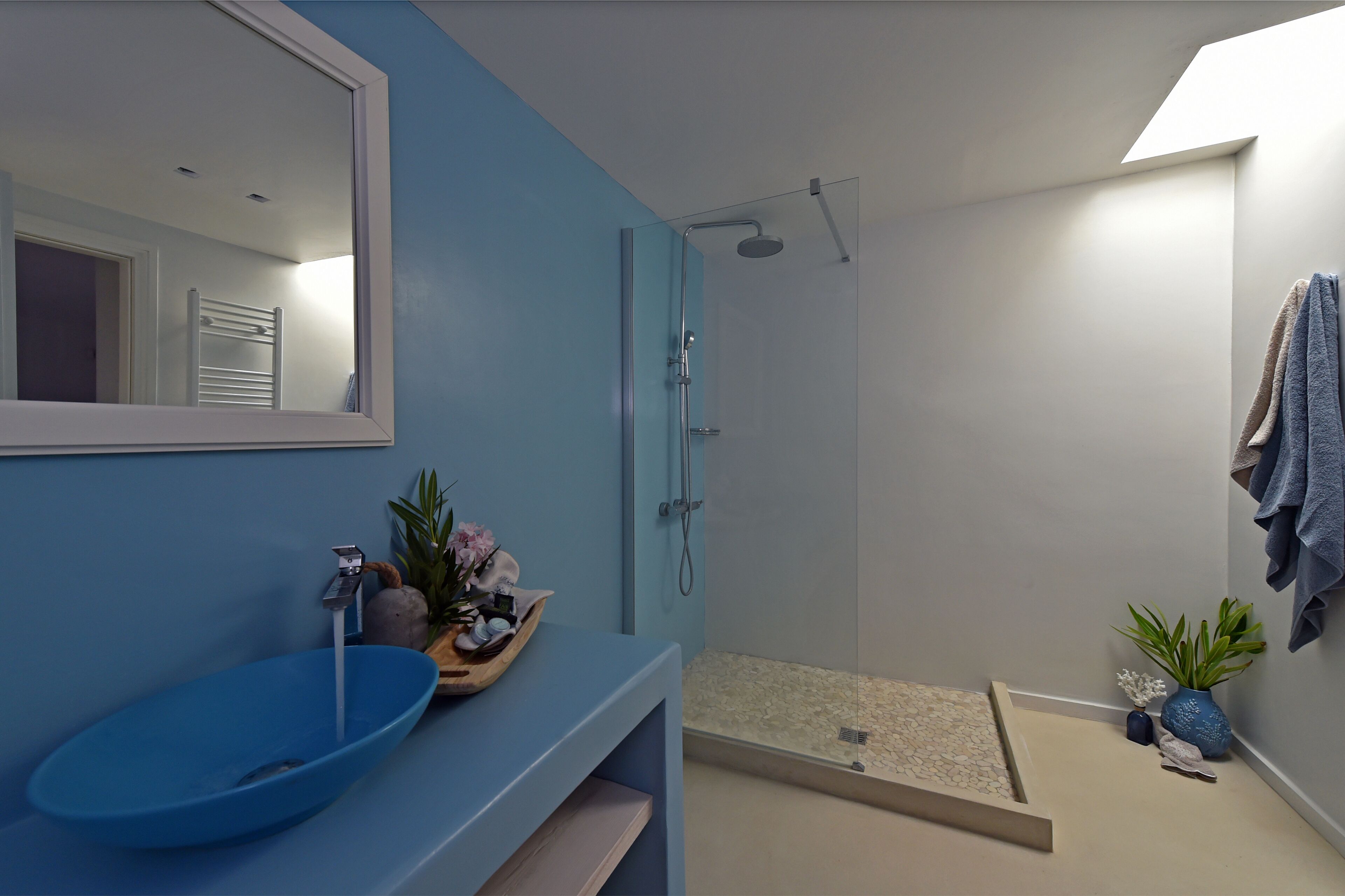 A modern bathroom with a blue vanity, a glass shower enclosure, and a towel rack.