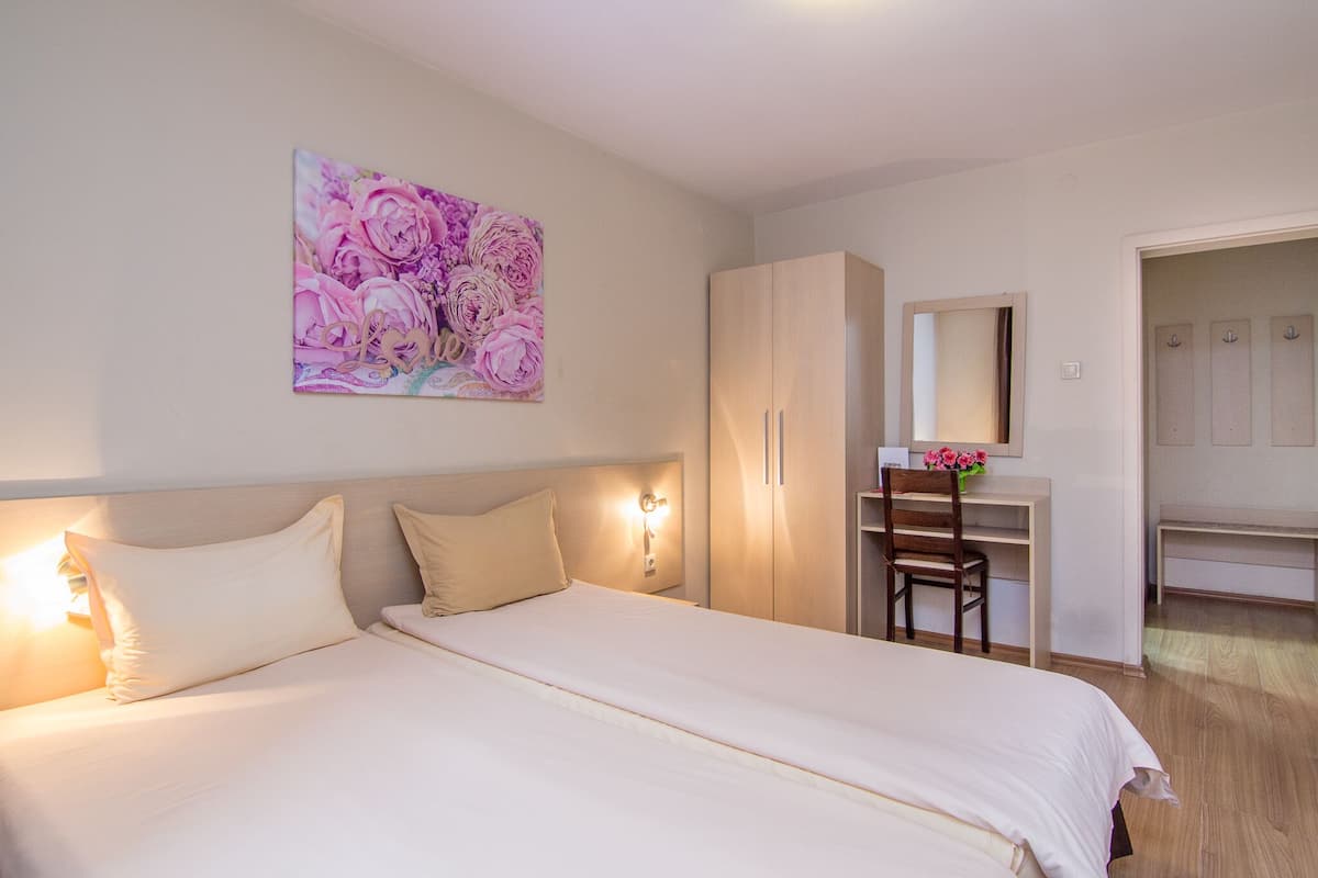 Un dormitorio con cama, escritorio, silla, armario y un cuadro en la pared.