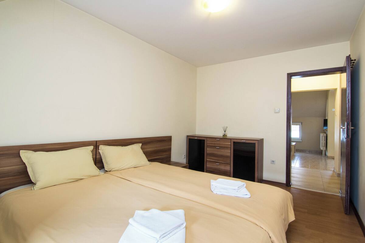 Una habitación de hotel con una cama grande, cabecero de madera, un escritorio con cajones y un espejo.