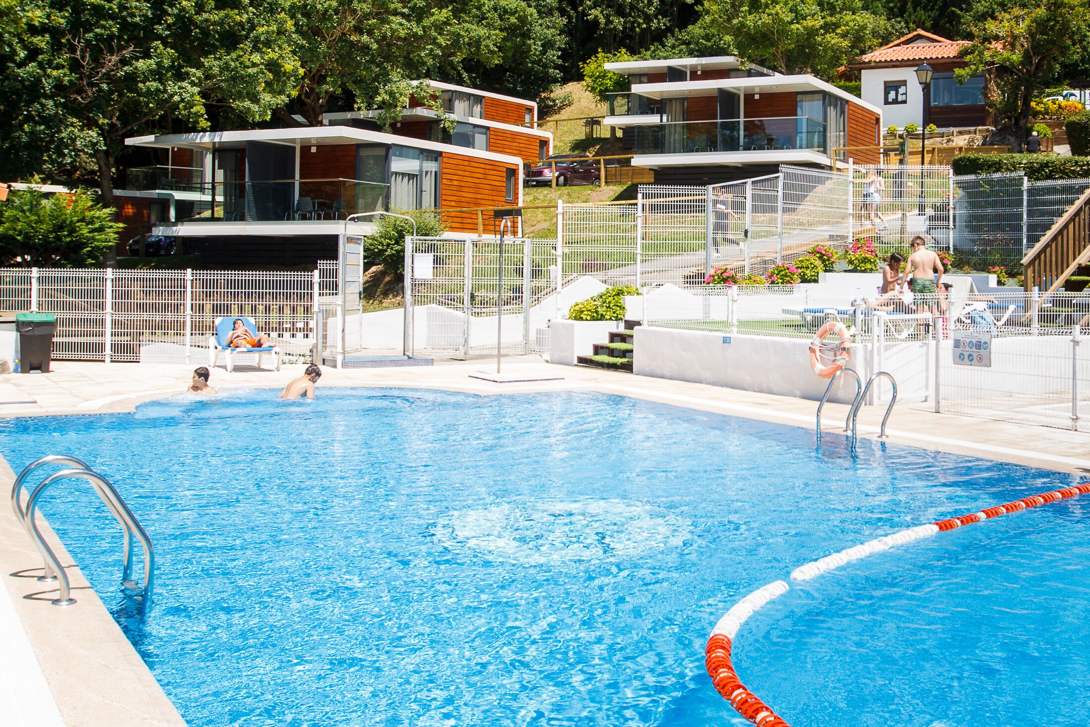 Een seizoensgebonden buitenzwembad, ligstoelen bij het zwembad