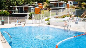 Een seizoensgebonden buitenzwembad, ligstoelen bij het zwembad