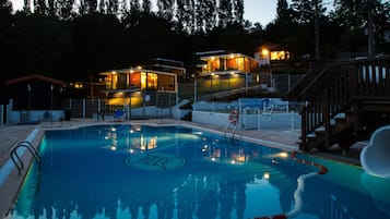 Una piscina al aire libre de temporada, sillones reclinables de piscina