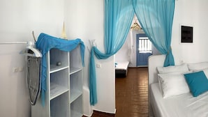A narrow hotel room with a bed, a shelf, and a curtain. - Nikoletta's Nest / House with large veranda  (4kms from Agia Anna,Plaka+Chora) (Naxos)
