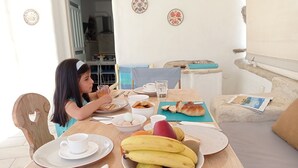 A dining table with plates, bowls, and cutlery, a sofa with cushions, and decorative plates on the wall. - Nikoletta's Nest / House with large veranda  (4kms from Agia Anna,Plaka+Chora) (Naxos)