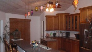 Una cocina con armarios de madera, encimera de granito y refrigerador de acero inoxidable.