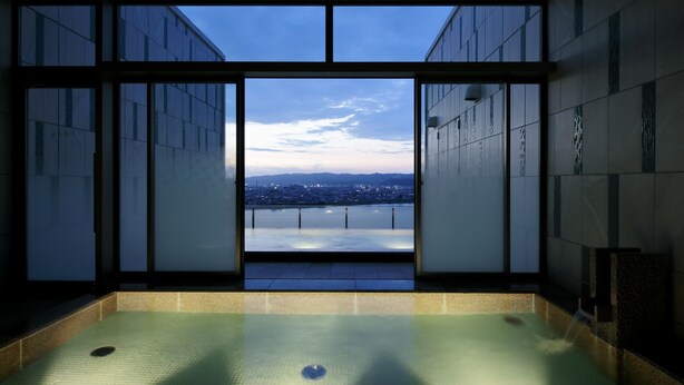 Una piscina interior moderna con vistas a un paisaje urbano a través de amplios ventanales.