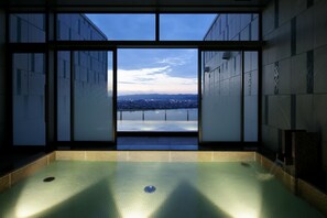 Una piscina interior moderna con vistas a un paisaje urbano a través de amplios ventanales.