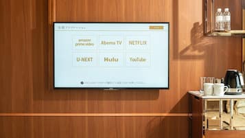 A wall-mounted TV displaying streaming services in Japanese.