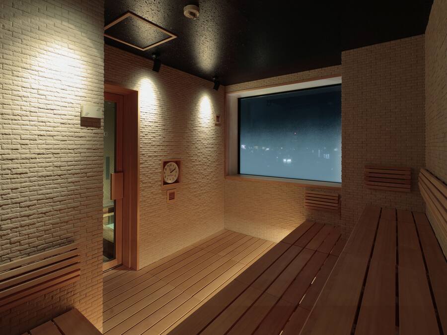 A room with a large window, wooden flooring, and a brick wall.