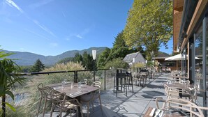 Un patio al aire libre con mesas y sillas, con vistas a un paisaje montañoso.