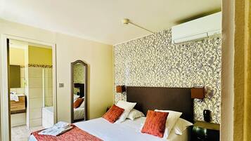 A hotel room with a bed, a mirror, a bedside table, and a carpeted floor.