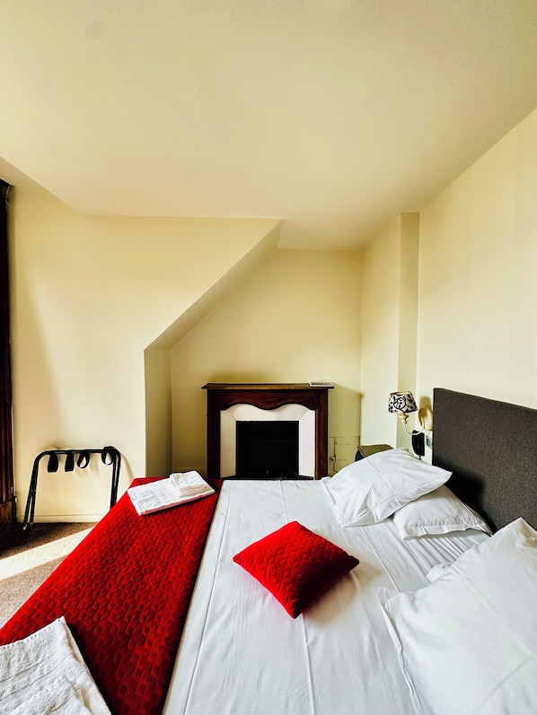 Habitación de hotel con cama, una silla, mesita de noche y lámpara.