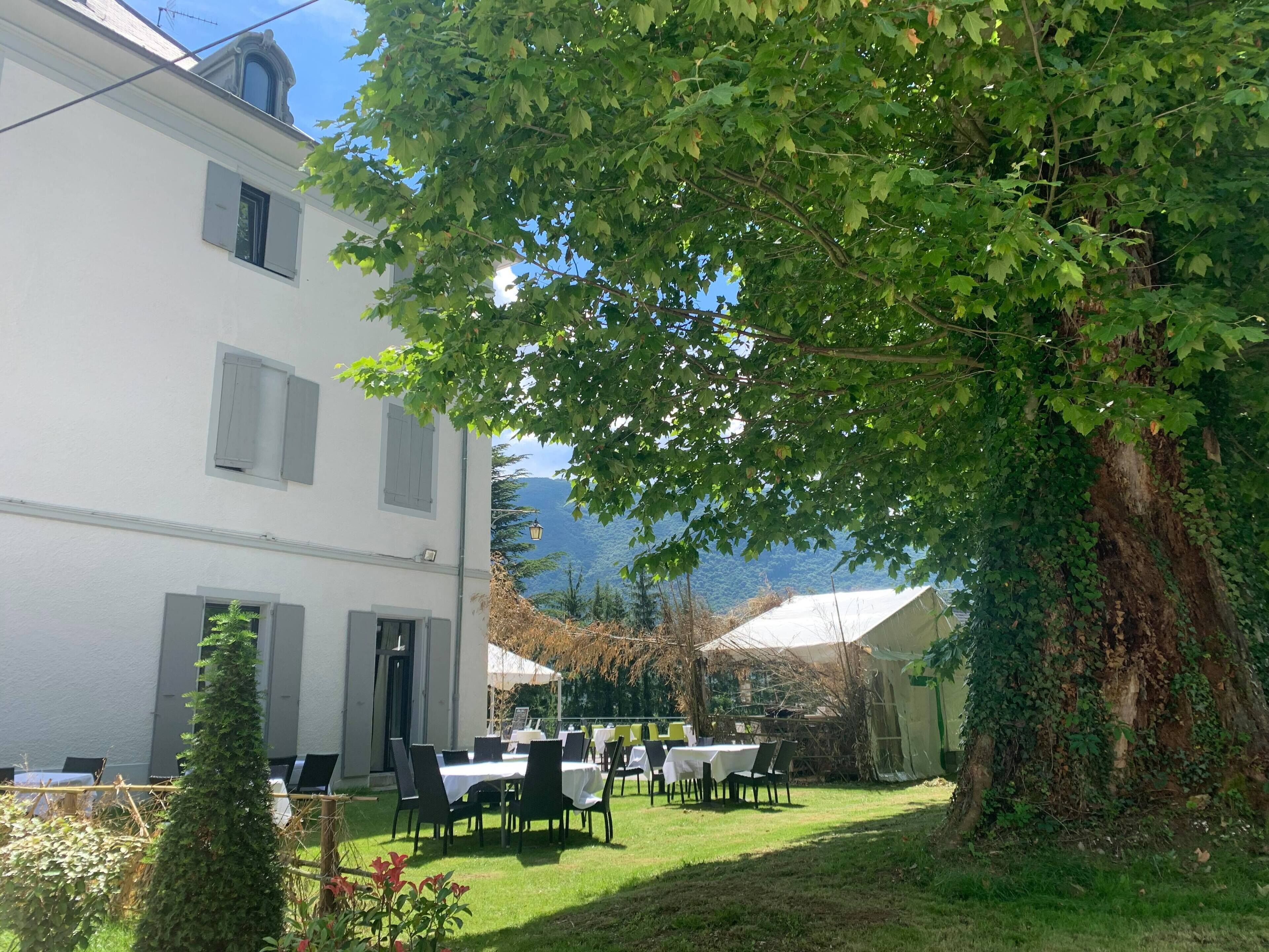 Un edificio blanco con un comedor al aire libre, que incluye mesas y sillas.