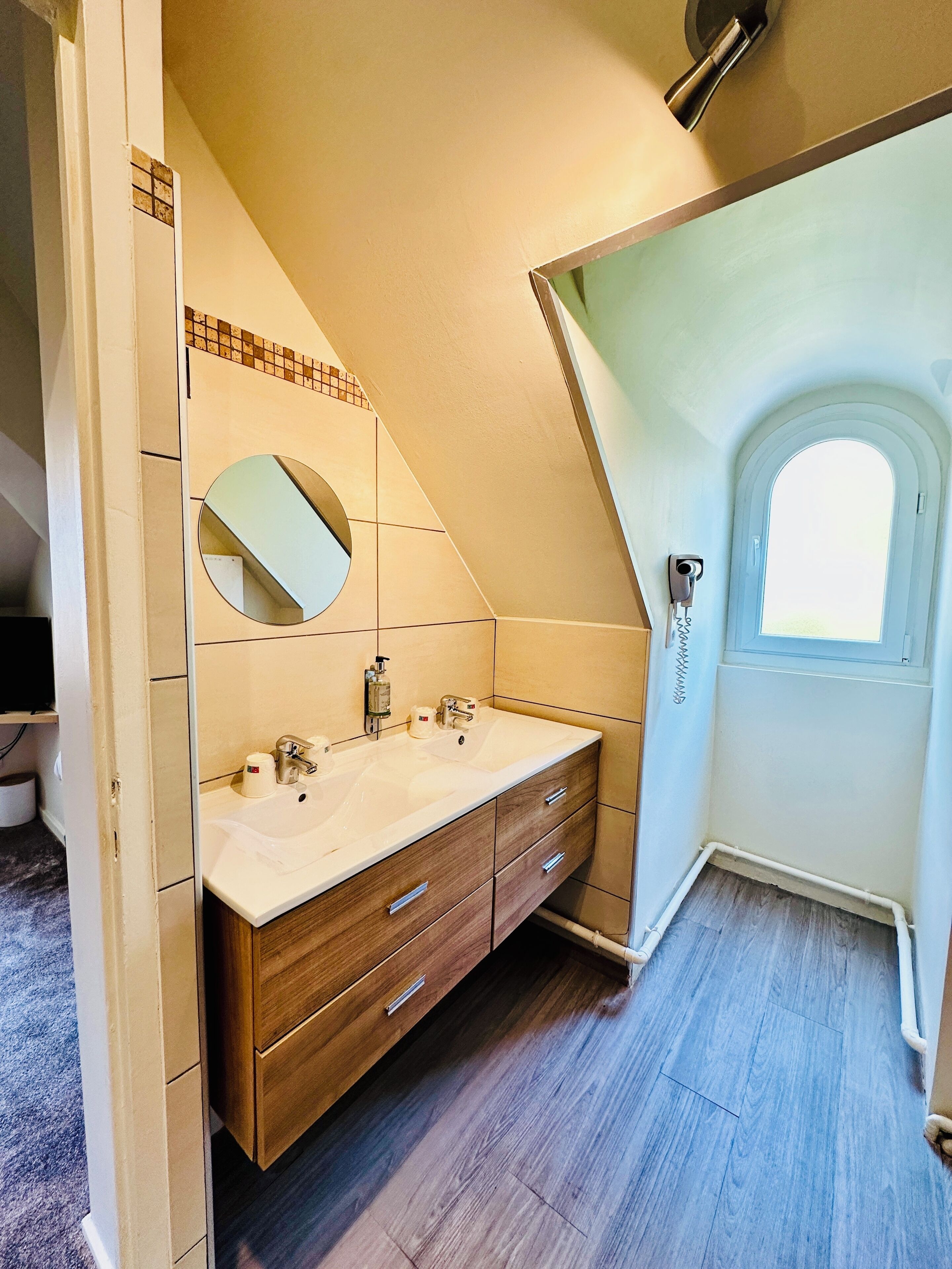 A modern bathroom with a large vanity, a mirror, and a window.