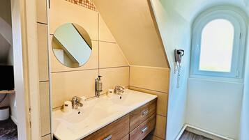 A modern bathroom with a large vanity, a mirror, and a window.