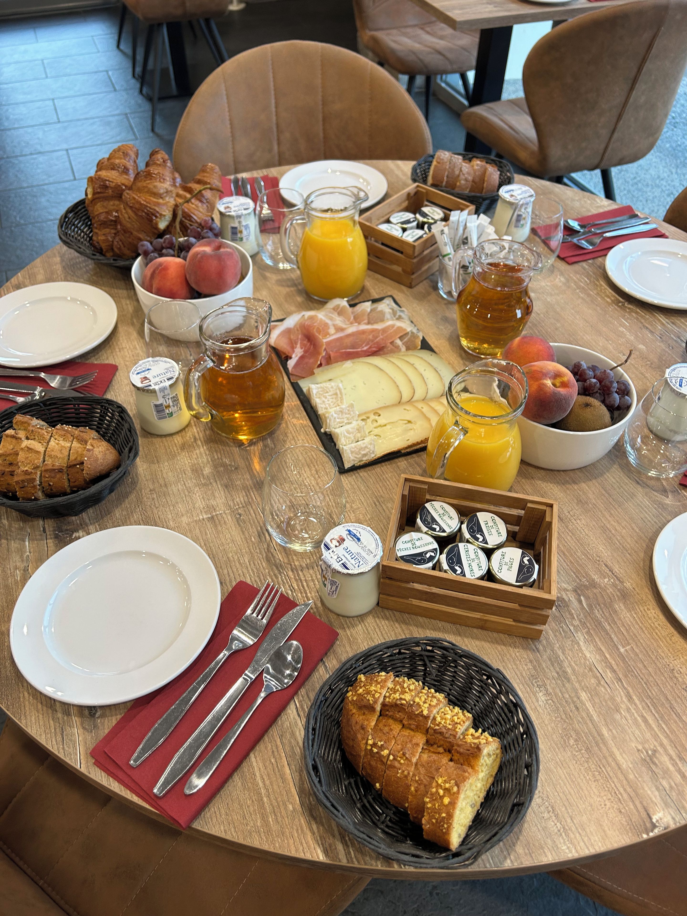 Ein Frühstückstisch mit Croissants, Käse, Obst und Getränken.