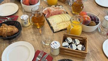 Ein Frühstückstisch mit Croissants, Käse, Obst und Getränken.