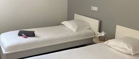 Een hotelkamer met twee bedden, een nachtkastje met een lamp en een wandlamp.