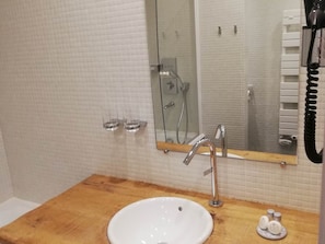 Une salle de bain avec un meuble-lavabo en bois, un lavabo blanc, un miroir et une douche.