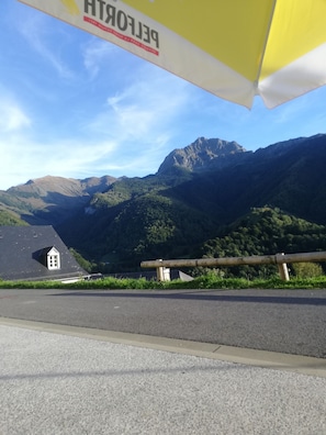Un paysage de montagne avec une route et un petit bâtiment doté d’un toit en pente.