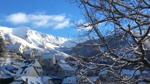 A snow-covered village with traditional buildings and a mountain in the background. - Auberge des Isards (Aydius)