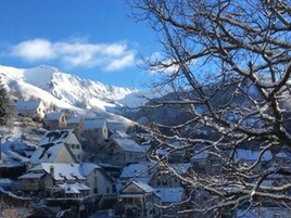 A snow-covered village with traditional buildings and a mountain in the background.